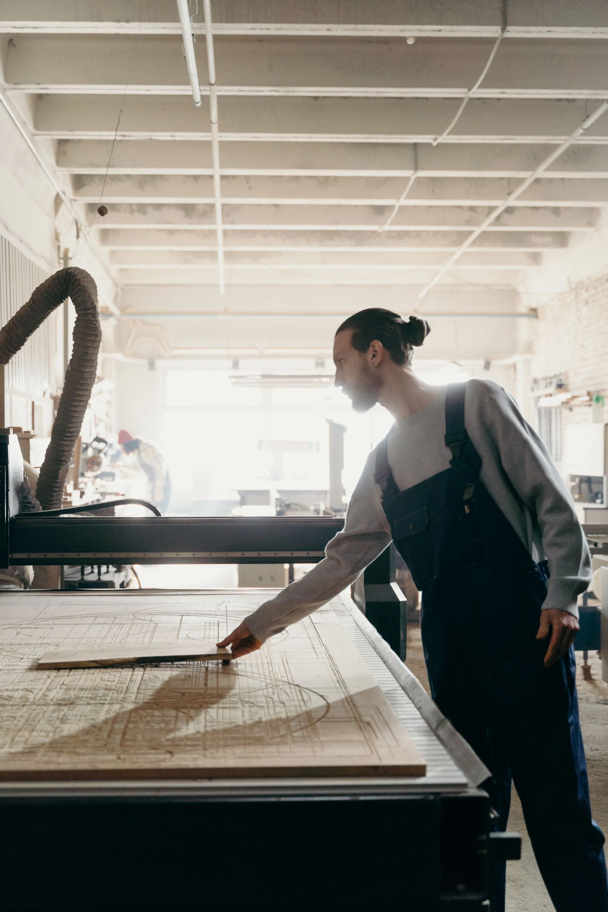 Handwerker an einem großen Zeichentisch in einer sonnigen Werkstatt